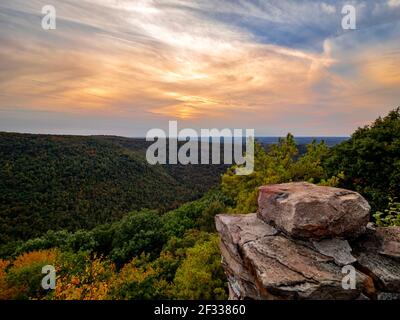 Blick auf die Berge und das Herbstlaub in Coopers Rock State Forest in West Virginia mit dem Sonnenuntergang golden Himmel eine Richtung und ein blauer Wirbel Stockfoto