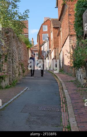 Ein Paar läuft in Lewes East Sussex eine steile, enge Straße hinunter Stockfoto