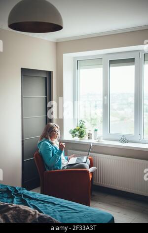 Seitenansicht Foto einer kaukasischen älteren Frau während des Gesprächs Ein Meeting auf dem Laptop, während Sie von zu Hause aus arbeiten Stockfoto