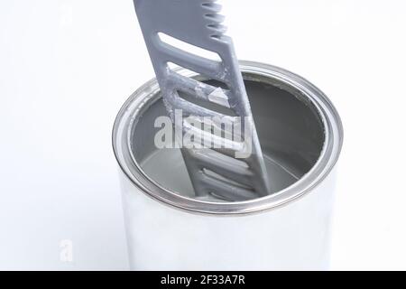 Ein Mann, der weiße Farbe in einer Dose auf weißem Hintergrund rührt. Renovierungskonzept. Stockfoto