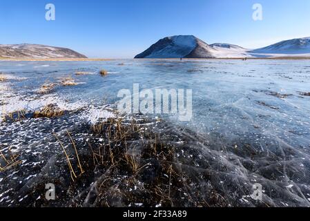 Blick auf schöne Zeichnungen auf dem Eis von Rissen und tiefen Gasblasen auf Oberfläche des Baikal-Sees im Winter, Russland Stockfoto