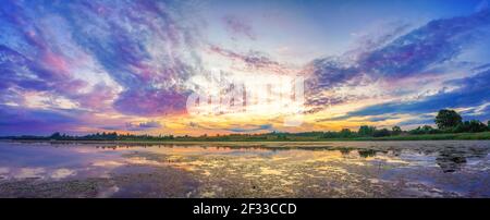 Panorama mit schönem bunten Sonnenaufgang über dem See Stockfoto