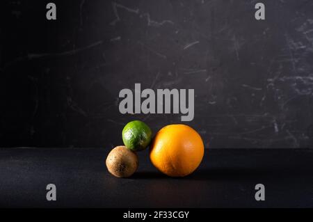 Figur aus verschiedenen Früchten auf schwarzem Hintergrund. Mehrfarbige Früchte auf schwarzem Hintergrund. Runde Formen von Früchten. Stockfoto