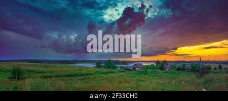 Panoramablick auf dramatischen Sonnenuntergang über dem See und dem alten Dorf Auf dem Land Stockfoto