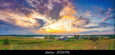 Panoramablick auf den hellen Sonnenuntergang über dem See und dem alten Dorf Auf dem Land Stockfoto