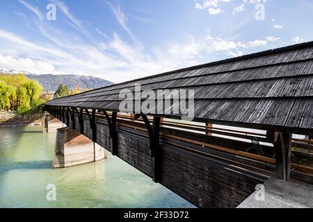 Weitwinkelansicht einer Fußgängerbrücke in Inssbruck, unter einem blauen Himmel mit gestreiften Wolken Stockfoto