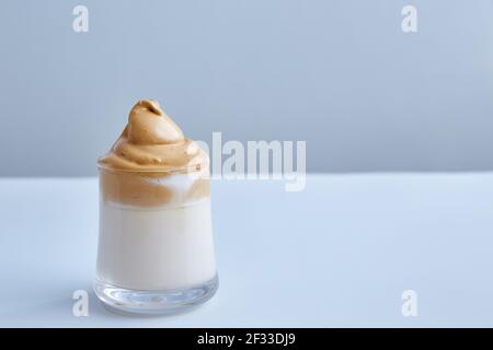 Dalgona-Kaffee ist der Modetrend dieser Saison. Traditionelle koreanische Küche. Milch mit Kaffee und Zuckerschaum. Minimalismus, grauer Hintergrund mit Kopie Stockfoto