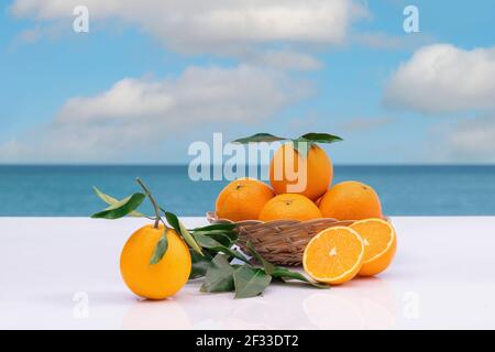 Frische Orangen in einem Weidenkorb mit Blättern auf einem unscharfen Hintergrund. Selektiver Fokus. Vitamin- und gesundes Lebensmittelkonzept. Stockfoto