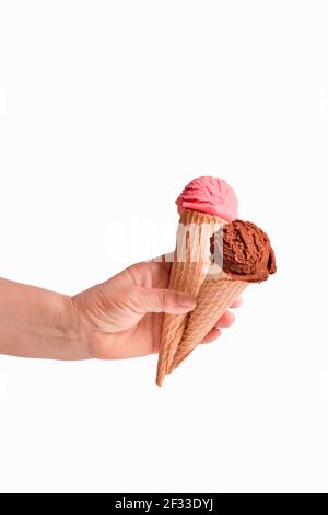 Weibliche Hand hält zwei Eiszapfen mit Schokolade und Erdbeer-Eisschaufeln. Selektiver Fokus und Nahaufnahme. Eiscreme-Konzept. Stockfoto