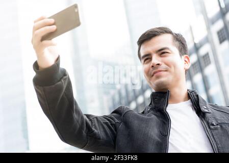 Junger Mann nimmt Selfie in der Stadt mit dem Smartphone Stockfoto