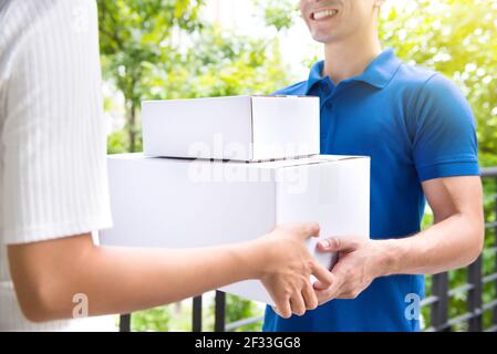 Lächelnde Lieferung Mann liefern Postpakete an eine Frau - Kurier- und Lieferdienstkonzepte Stockfoto