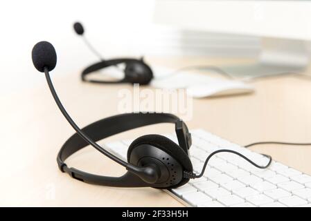 Mikrofon-Headsets auf dem Tisch mit Computer-Tastatur in Anruf Zentrieren Stockfoto