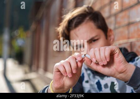 Ein Teenager bricht eine Zigarette und protestiert gegen das Rauchen. Nahaufnahme. Das Konzept der Jugendlichen Rauchsucht. Stockfoto