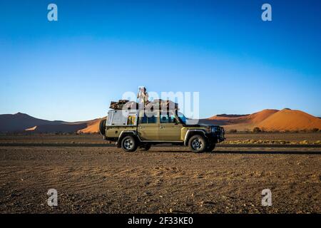 Ein Fotograf auf einem 4x4 in der Wüste von sossusvlei, namibia. Stockfoto