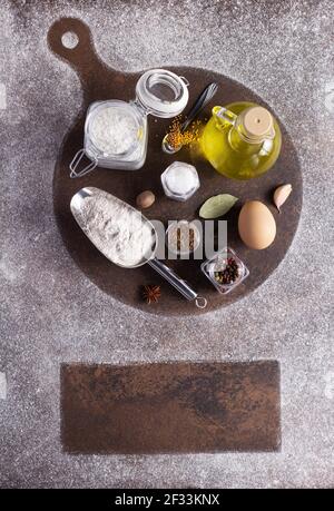 Streumehl und Backzutaten für selbstgebackenes Brot auf dem Tisch. Food for Dough Rezept Draufsicht auf Stein Hintergrundtextur mit Kopie Stockfoto