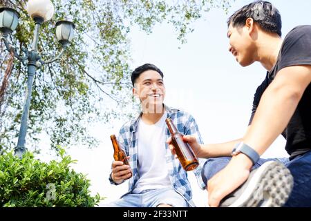Zwei glückliche asiatische Männer trinken Bier und verbringen lustige Zeit Gemeinsam im Freien Stockfoto
