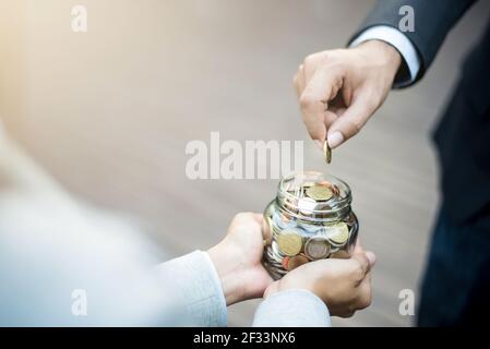 Geschäftsmann Hand Putting Geld (Münze) in das Glas gehalten Von einer Frau Stockfoto