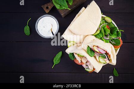 Pita gefüllt mit Huhn, Tomate, Gurke und Spinat auf Holzgrund. Nahöstliche Küche. Draufsicht, oben Stockfoto