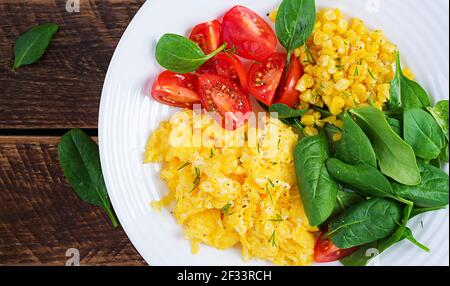 Frühstück. Rührei mit Kirschtomaten, Spinat und Mais. Draufsicht, flach liegend, oben Stockfoto