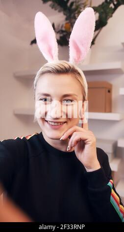 Glückliche junge Frau, die einen Videoanruf hat, während sie Hasenohren trägt. Hochwertige Fotos Stockfoto