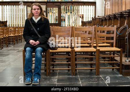 Breda, Niederlande. Mittlere Erwachsene kaukasische Frau, die in einer mediavalen protestantischen Kirche nachdenkt und betet. Stockfoto