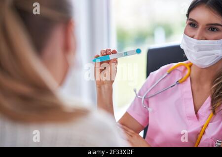 Arzt in Maske erklärt Diagnose zu ihrer weiblichen Patientin Stockfoto