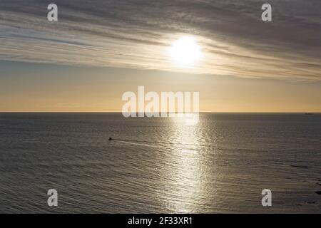 Ein kleines privates Fischerboot in der Bucht von Auchmithie, das sich an einem ruhigen frühen Morgen zu seinen Krabbenköpfen hinzieht, mit seinem Wake, der sich dahinter erstreckt. Stockfoto