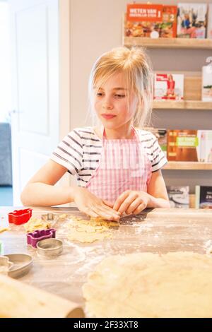 Kaatsheuvel, Niederlande. Schulmädchen Yara backen Cookies innerhalb sie zuhause Küche Stockfoto