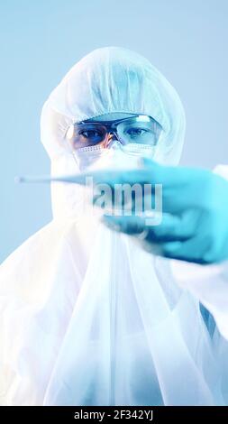 Ärztin in einem Schutzanzug mit einem Thermometer. Hochwertige Fotos Stockfoto