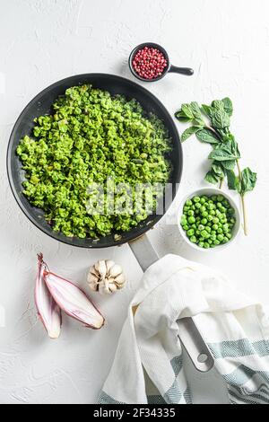 Hausgemachte Mushy Erbsen gekochte Pfanne und Erbsen in Schüssel Mit Minze Schalotte Pfeffer und Salz auf weißem Stein Oberfläche Bio-Keto Lebensmittel über dem Foto oben Stockfoto