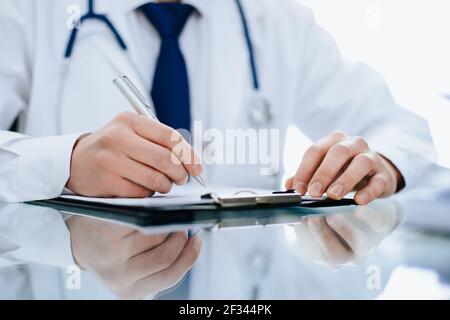 Nahaufnahme. Arzt macht Notizen in der Zwischenablage. Stockfoto