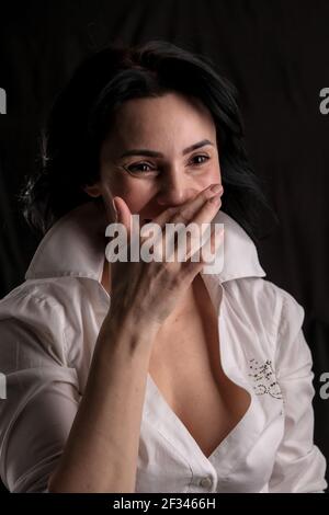 Portrait der schönen reifen Brünette Frau in weißem Hemd isoliert auf schwarzem Hintergrund gekleidet, kopieren Raum Stockfoto