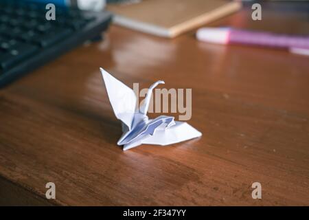 Konzept für psychische Erkrankungen. Beschädigter Origami-Papierkran auf Holztisch. Stockfoto