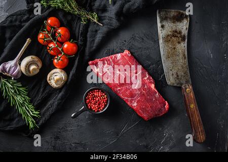 Roh, Klappe oder Flanke, auch bekannt Bavette Steak nahe Metzgermesser mit rosa Pfeffer und Rosmarin. Schwarzer Hintergrund. Draufsicht. Stockfoto