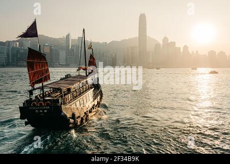 Der Blick von Kowloons Tsimshatsui Kai über Victoria Hafen auf Hong Kong Insel, während das Aqua Luna, ein traditioneller Trödel, in die Segel setzt Stockfoto