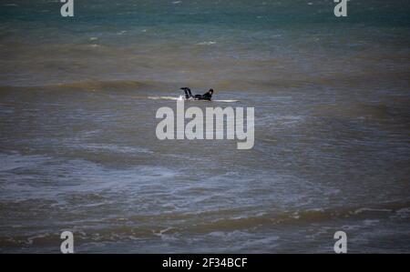 Ein lokaler Surfer am Strand von West Wittering hält sich in sozialer Distanz, da der Parkplatz geschlossen werden muss, nachdem am Samstag Tausende von Menschen auftauchten. Stockfoto