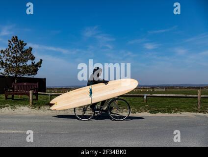 Ein lokaler Surfer, der den West Wittering Beach verlässt, hält sich in sozialer Distanz, da der Parkplatz geschlossen werden muss, nachdem Tausende von Menschen am Satur auftauchten Stockfoto