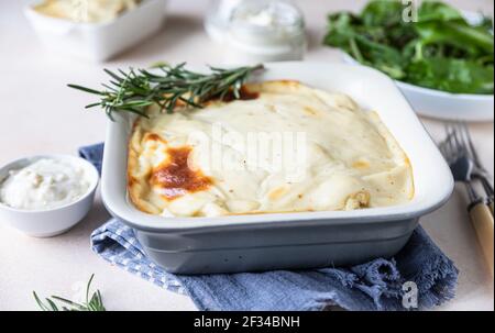 Blumenkohlgratin mit Huhn und Bechamelsauce mit Rosmarin in einer Auflaufform dekoriert. Pikanter Auflauf. Selektiver Fokus. Stockfoto