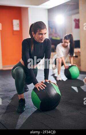 Fokussierte Brünette Dame in athletischen tragen arbeiten mit Ball Stockfoto