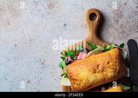 Rindersteak-Sandwich mit Rucola, Tomate und Parmesan auf einem Holzbrett. Comfort Food Konzept. Stockfoto