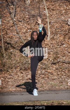 Eine flinke, flexible Frau in den Fünfzigern führt täglich einen meditativen Yoga-Kurs in einem Park in Queens, New York City. Stockfoto