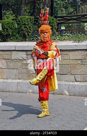 Foto eines asiatischen Straßenmusikers in einem bunten Kostüm tanz für Spenden im Union Square Park in New York Stadt Stockfoto