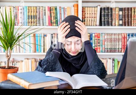 Gelangweilte arabische muslimische Frau mit Online-Technologie Stockfoto