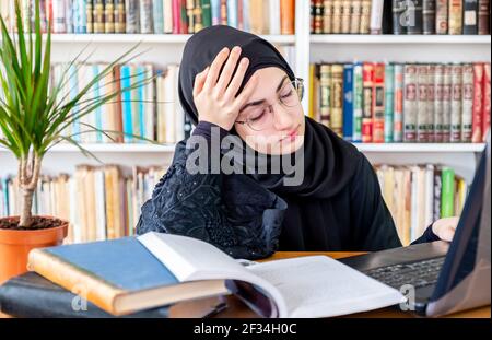 Gelangweilte arabische muslimische Frau mit Online-Technologie Stockfoto