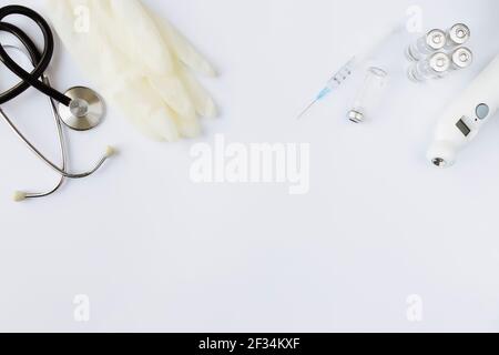 Medizin Behandlung, Impfkonzept. Flasche mit Impfstoff und Injektionsspritze, elektronischem Thermometer, Stethoskop und Impfstofffläschchen auf weiß b Stockfoto