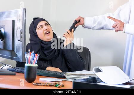 Arabisch-muslimische Angestellte, die von ihrem Chef wegen des Gesprächs beschimpft wurde Am Telefon bei der Arbeit Stockfoto