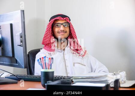 Arabisch-muslimischer Mitarbeiter glücklich an seinem Arbeitsplatz Stockfoto