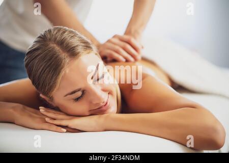 Professionelle Masseur tun therapeutische Massage. Frau genießt Massage in ihrem Haus. Junge Frau bekommen entspannende Körpermassage. Stockfoto