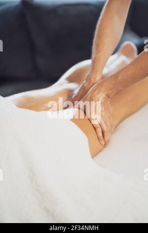 Professionelle Masseur tun therapeutische Massage. Frau genießt Massage in ihrem Haus. Junge Frau bekommen entspannende Körpermassage. Stockfoto