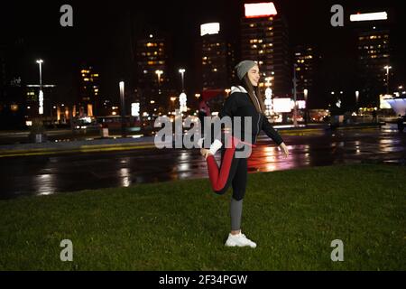 Frau streckt ihre Beine vor ihrem Outdoor-Training Stockfoto